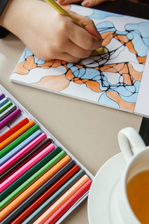 TVER, RUSSIA - FEBRUARY 11, 2023: a young woman draws neurography at a table at a psychological session, a neurographic resunok with a pencil to remove oranicheniyのeditorial素材