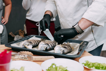 Baked Dorado fish in the oven. Cooking Dorado fish in the cooking class. Baked fish, selective focus. Home food, cooking at home.の写真素材