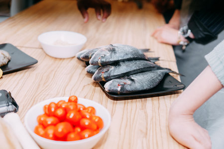 Raw Dorado fish on a black plate. Cooking Dorado in a cooking class. Raw fish, close-up. Homemade food, cooking at home.の写真素材