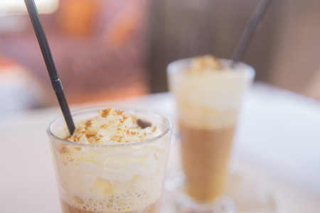 coffee is served in a tall glass glass with a straw. The concept of coffee drinks from the bar menuの写真素材