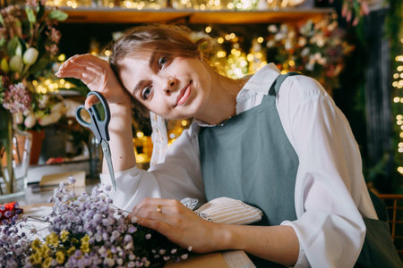 A woman in her florist shop collects bouquets of flowers. The concept of a small business. Bouquets of tulips for the holiday on March 8.の写真素材