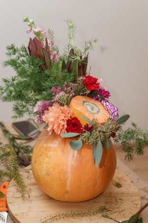 Flower arrangement in a pumpkin, autumn interior decor. Creating handmade autumn decor.の写真素材