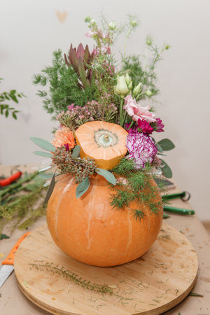 Flower arrangement in a pumpkin, autumn interior decor. Creating handmade autumn decorの写真素材