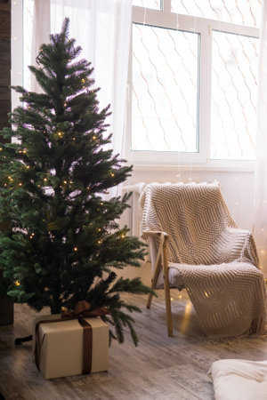 Home New Years interior. Christmas tree with gifts, decorated with garlands. Cozy atmosphere of a home holiday, loft design of the room, Scandinavian styleの写真素材