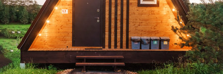 The concept of glamping and renting a chalet for weekend. Wooden house with a veranda in nature...