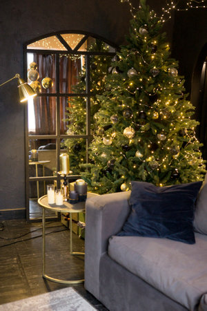 Christmas interior with a beautiful Christmas tree, sofa, light bulbs and dark backgroundの写真素材