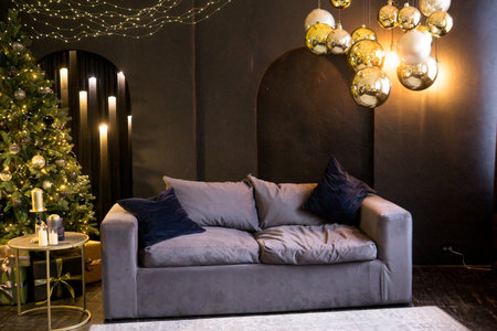 Christmas interior with a beautiful Christmas tree, sofa, light bulbs and dark backgroundの写真素材