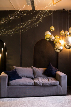 Christmas interior with a beautiful Christmas tree, sofa, light bulbs and dark backgroundの写真素材