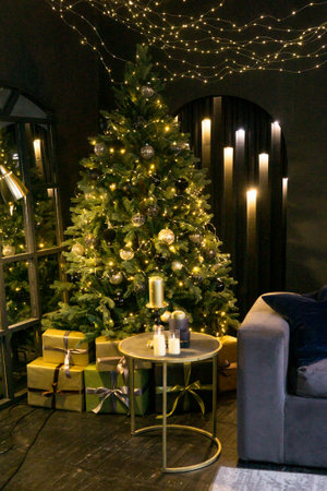 Christmas interior with a beautiful Christmas tree, sofa, light bulbs and dark backgroundの写真素材