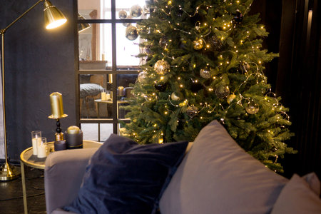 Christmas interior with a beautiful Christmas tree, sofa, light bulbs and dark backgroundの写真素材