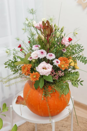 Flower arrangement in a pumpkin, autumn interior decor. Creating handmade autumn decor.の写真素材