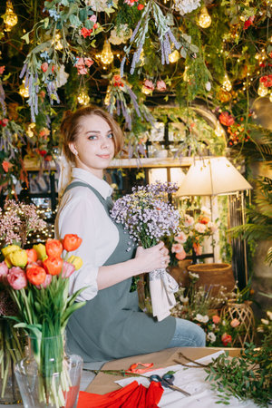 A woman in her florist shop collects bouquets of flowers. The concept of a small business. Bouquets of tulips for the holiday on March 8の写真素材