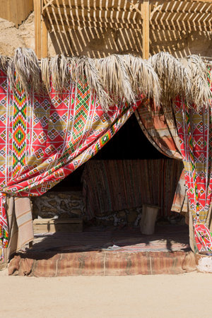 Traditional middle eastern style tent decorated with colorful fabric and palm leaf roof for summer resort and desert travel concept and holiday getaway destinationの写真素材