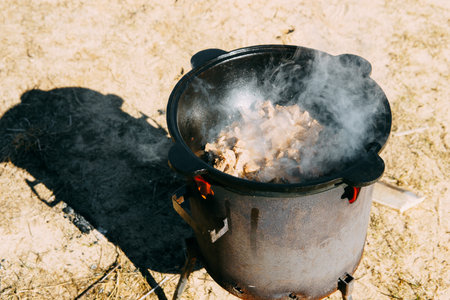 Meat cooking in cauldron outdoor. Plov recipe with meat. Cooking food street. Traditional cuisine and oriental dishの写真素材