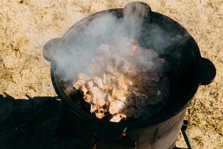 Meat cooking in cauldron outdoor. Plov recipe with meat. Cooking food street. Traditional cuisine and oriental dishの写真素材