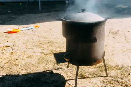 Steel kazan, a large cast iron cauldron, on a fire pit for cooking outdoors. Outdoor cooking concept...