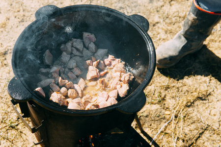 Meat cooking in cauldron outdoor. Plov recipe with meat. Cooking food street. Traditional cuisine and oriental dishの写真素材