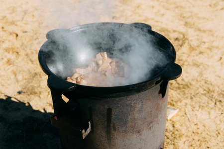 Meat cooking in cauldron outdoor. Plov recipe with meat. Cooking food street. Traditional cuisine and oriental dishの写真素材
