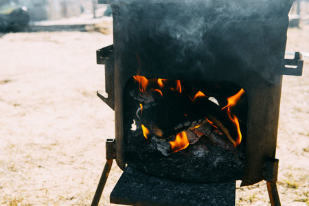 Outdoor cooking fire in a metal stove. Flame and smoke coming from burning wood in a campfire oven...