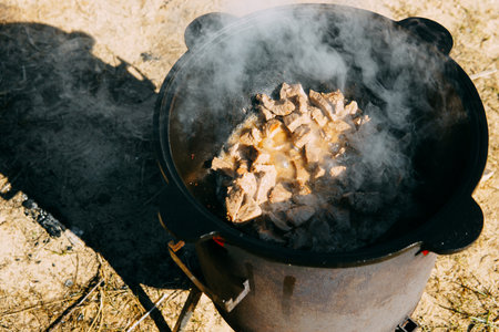 Meat cooking in cauldron outdoor. Plov recipe with meat. Cooking food street. Traditional cuisine and oriental dish.の写真素材