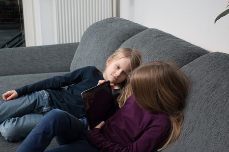 Girl hides screen from younger sisterの写真素材