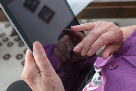 hands of 95 year old woman typing on a mobile divice or ipadの写真素材