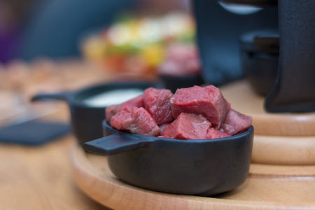 A bowl of beef  cut in pieces on a wooden plate ready for fondueの写真素材