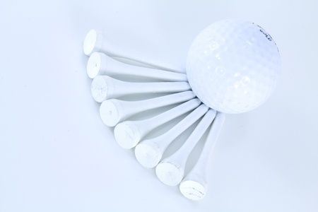 Golf Ball on a white background resting against several white teesの写真素材