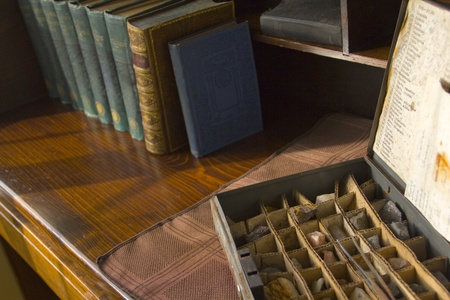 roll top desk with antique gemm collection and old books bathed in sunlightの写真素材