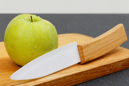 Small wet green apple and knife on wooden cutting boardの写真素材