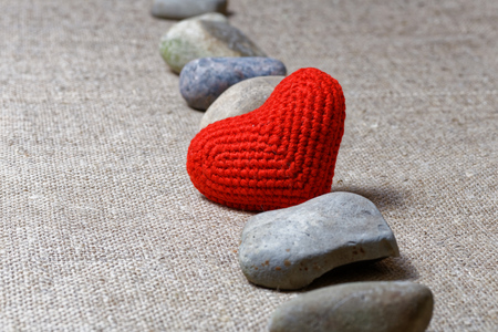 Red heart in row of stones on textile background. Shallow focus on heart.の写真素材