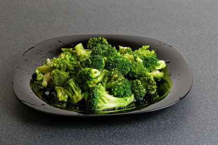 Frozen raw broccoli in black plate on dark tableの写真素材