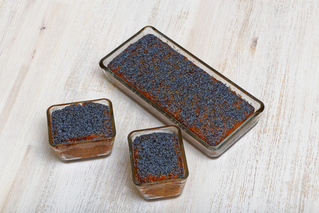 Three lemon poppy cakes in glass forms on white wooden tableの写真素材