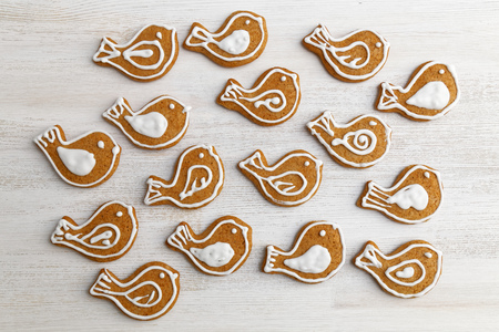 Gingerbread cookies with honey and cinnamon in the form of birds decorated with white icing on white wooden table.の写真素材