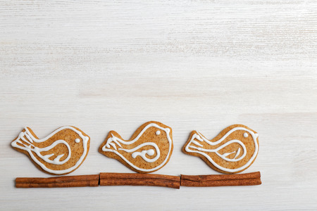 Gingerbread cookies with honey and cinnamon in the form of birds decorated with white icing on white wooden table.の写真素材