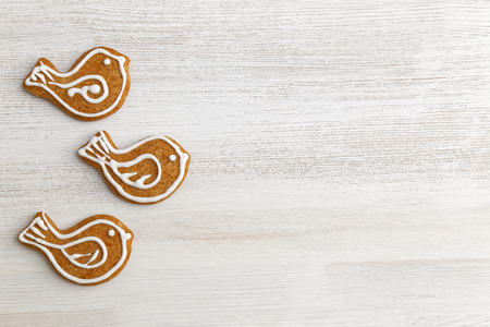 Gingerbread cookies with honey and cinnamon in the form of birds decorated with white icing on white wooden table.の写真素材