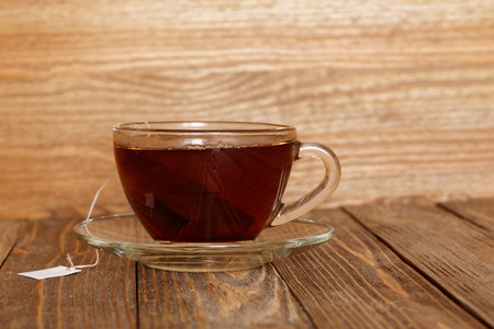Closeup cup of tea on wooden table. Tea bag with blank white label. Directly view.の写真素材