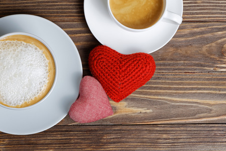 Closeup pair handmade hearts and two cups coffee on wooden table on Valentines day. Top view.の写真素材