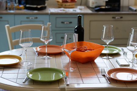 Preparing for the holiday. Wine bottle, empty wine glasses and empty plates on the table against a...