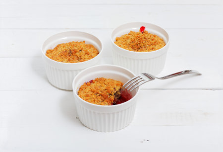 Three crumbles  with raspberries, gooseberries, blackberries and cinnamon. English dessert in a...