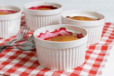 Homemade cobblers with raspberries and gooseberries in the white ceramic mold for baking on white...