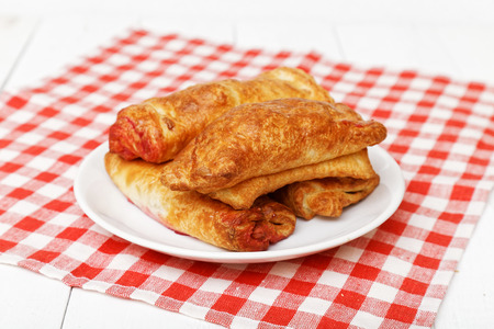 Homemade strudels with cherries in white dish on white wooden table. Shallow focus.の写真素材