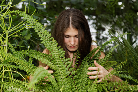 Portrait pretty young girl hugging fern in the blurry background of foliage forestの写真素材