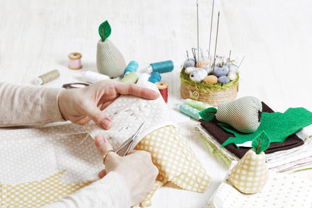 Handicrafts. The needlewoman cuts out a pattern for the handmade toy with scissors. There are...