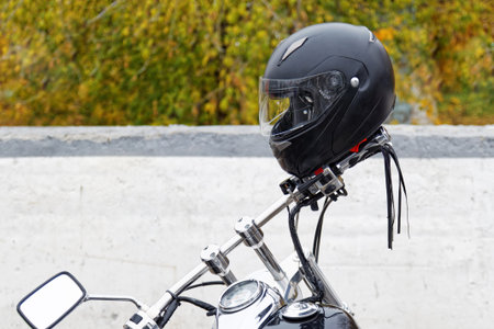Black moto helmet on motorcycle handlebars against blurred background