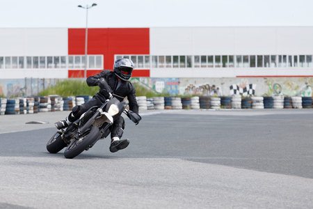 Motorcycle racer in black uniform leaning into a fast corner on track