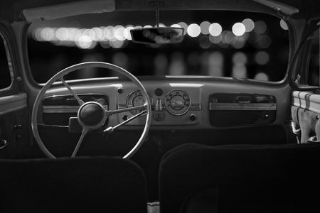 Old cabin, console and steering wheel in a vintage retro car. Night lights. Black and white image.の写真素材