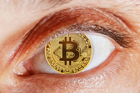 Macro detail photo of open human eye with coin bitcoin instead of pupilの写真素材
