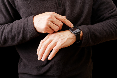 Closeup hands of man using his smartwatch. Isolated on black.の写真素材