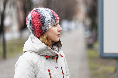 Portrait in profile of a young woman dressed in a light autumn jacket. Blurred background.の写真素材